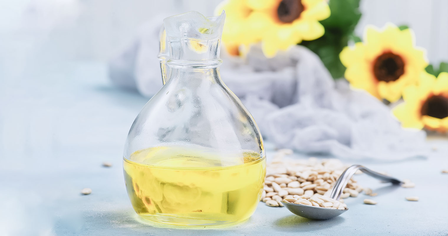 A jar of sunflower oil with sunflower and seeds in the background